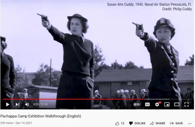 A screenshot of a YouTube video player showing a woman in Navy uniform aiming a pistol, with an overlaid caption reading Susan Ahn Cuddy, 1943, Naval Air Station Pensacola, Fl., Credit: Philip Cuddy