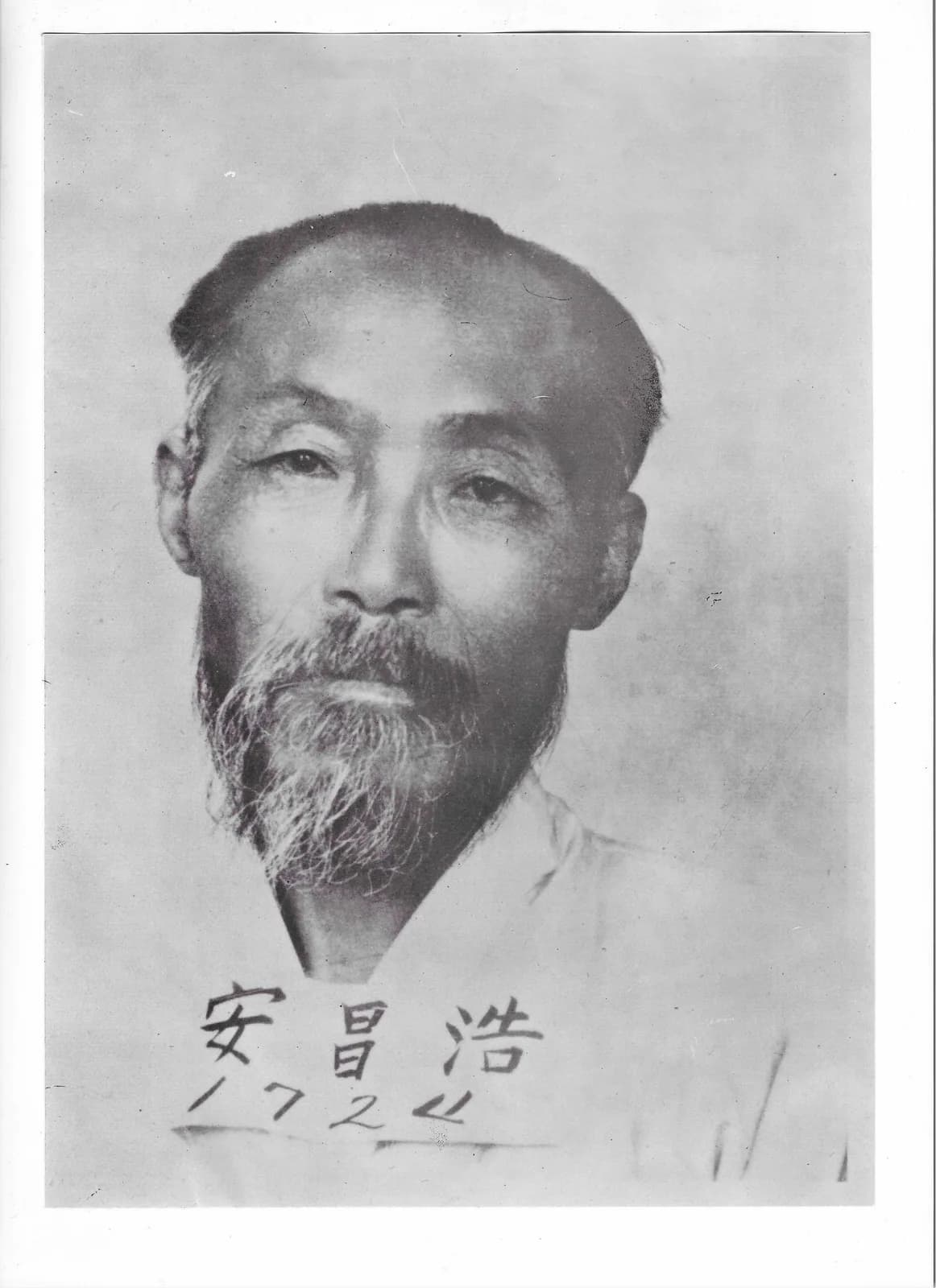 Head-and-shoulders prison photograph of an older man with a grey beard, the name 安昌浩 and a number written across the lower edge