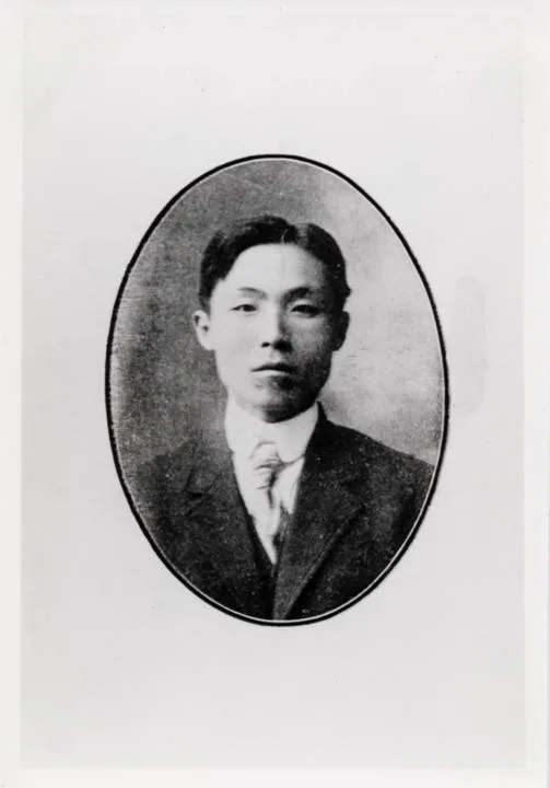 Oval studio portrait of a young man in a dark suit and tie